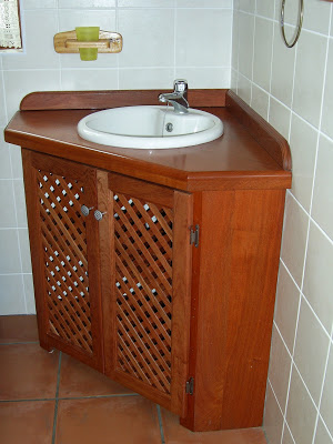 Wash basin cabinet built into the corner of the bathroom. Made of rosewood and with louver doors 