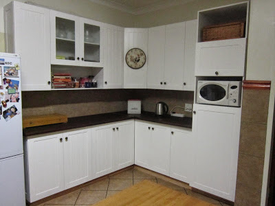 The doors of the farm style kitchen cupboards are made of supawood sprayed with white paint. The top and base are made of laminated stained saligna