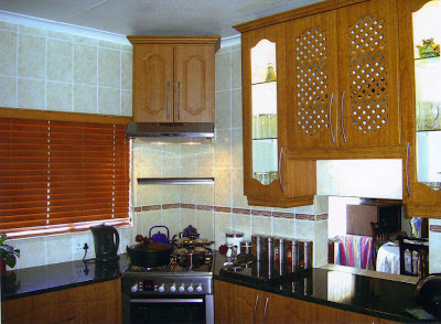The lit up cupboards with glass and louver doors give an interesting variation to the solid doors. The crown mouldings on top give a fine finish to the cupboards. The extractor which absorbs the smell of the food from the stove is fitted beneath the cupboard in the corner  